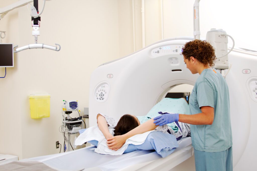 Woman entering CT Machine feet first with the assistance of CT technologist.