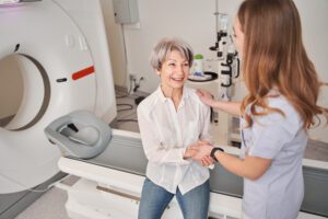 Female patient sitting on bed greeting technologist.