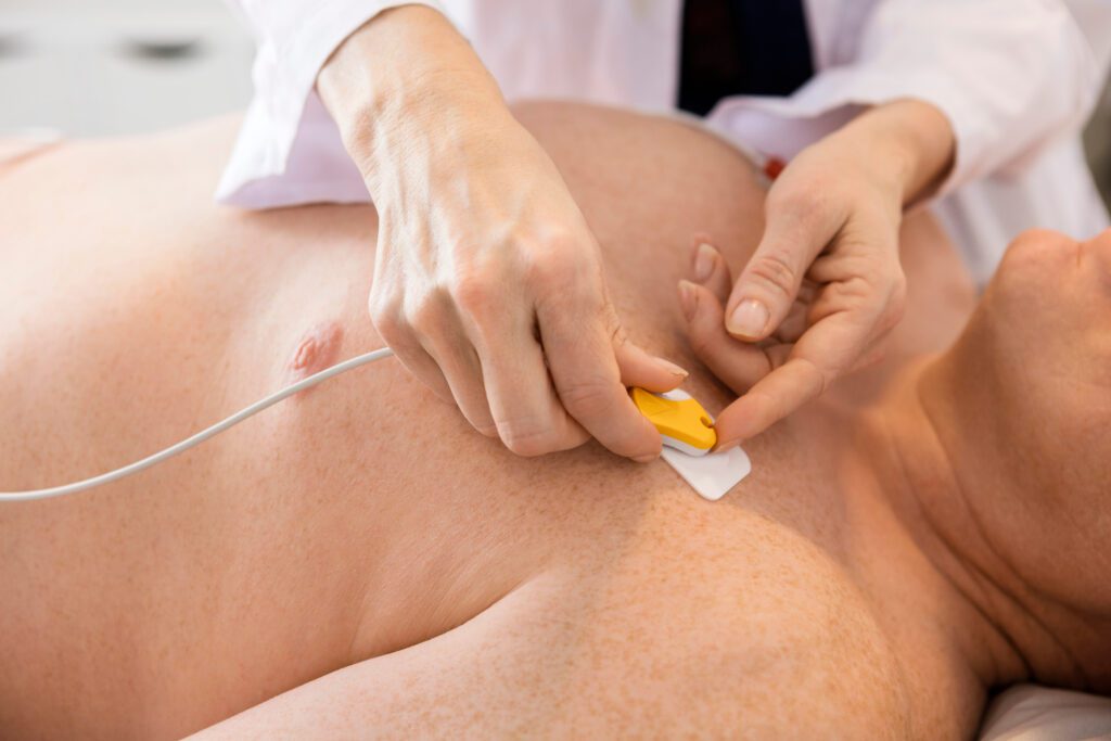 Closeup of doctor's hands attaching electrodes on patient's chest